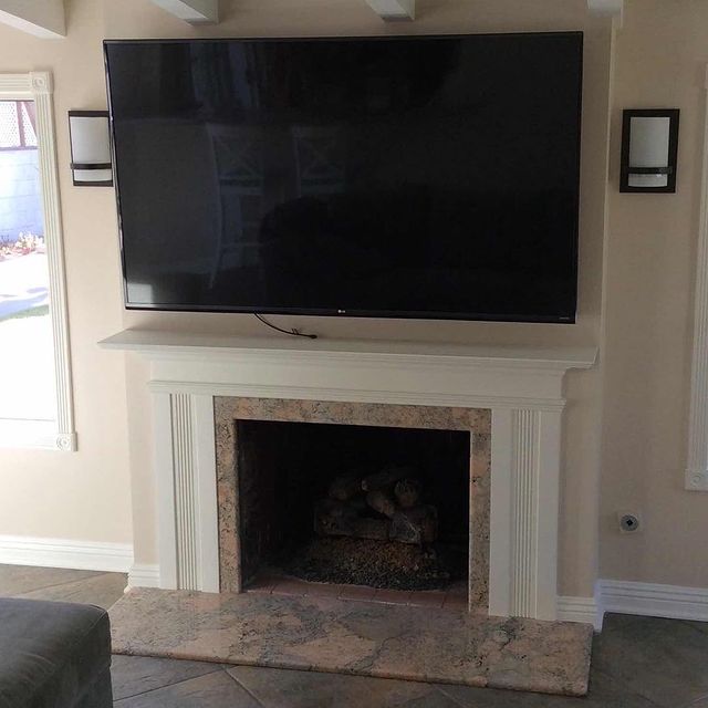 A brand new white mantle, with a fireplace surround and mounted tv.