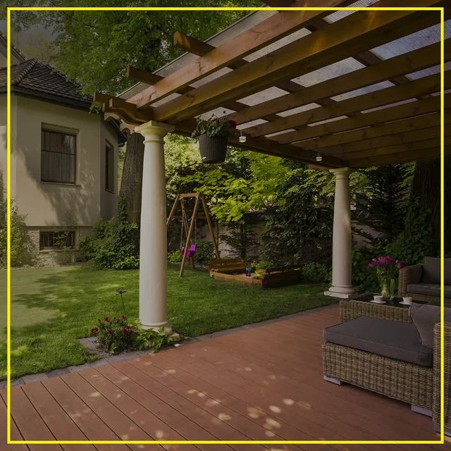 Outdoor yard with green grass, deck, and white pillars.