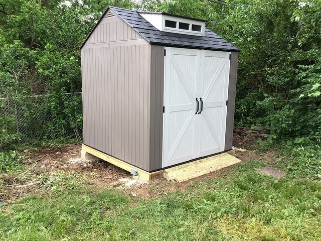 Small brown wooden shed with white doors.