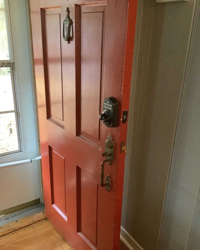 Black smart lock installed on orange front door