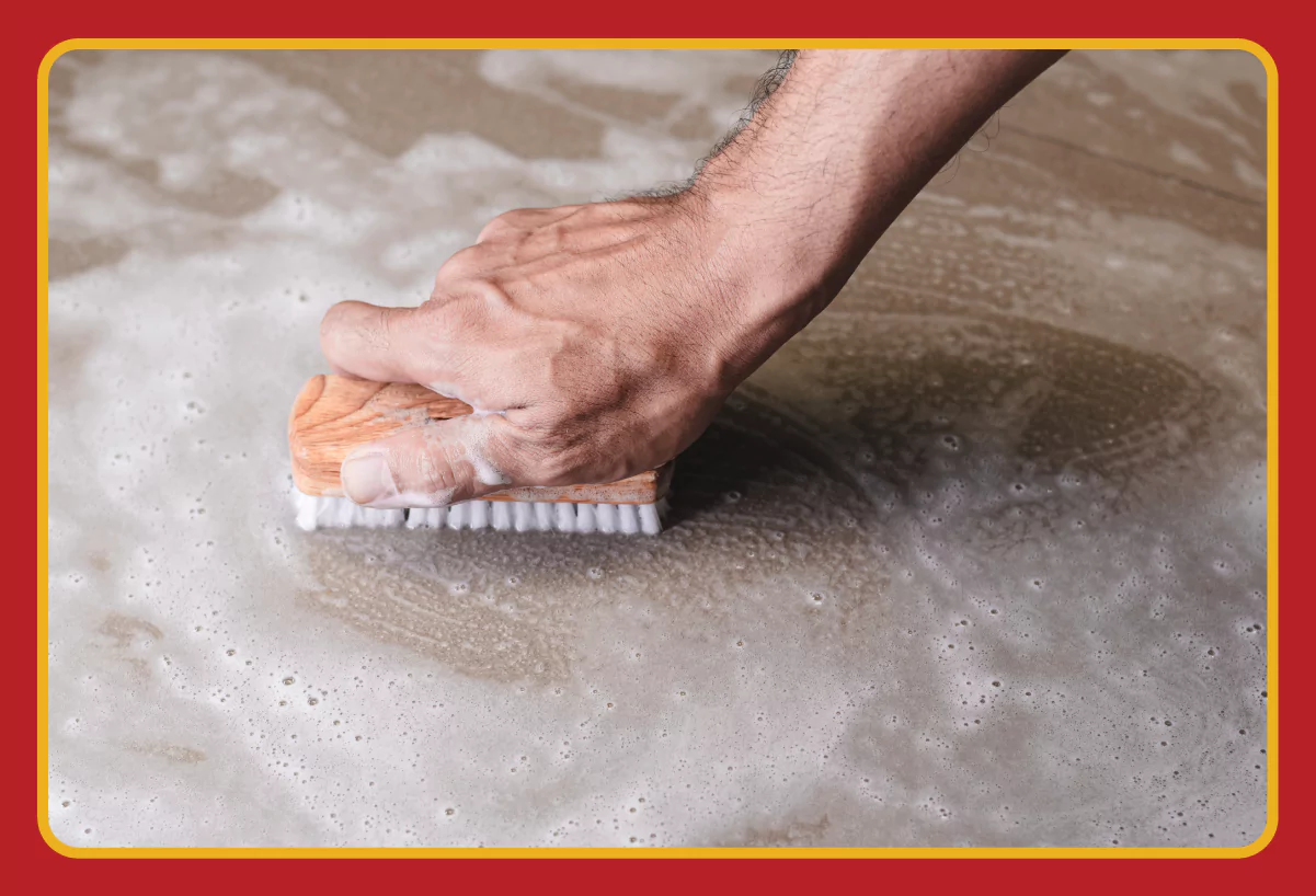 A person cleaning concrete floor with a scrub brush.