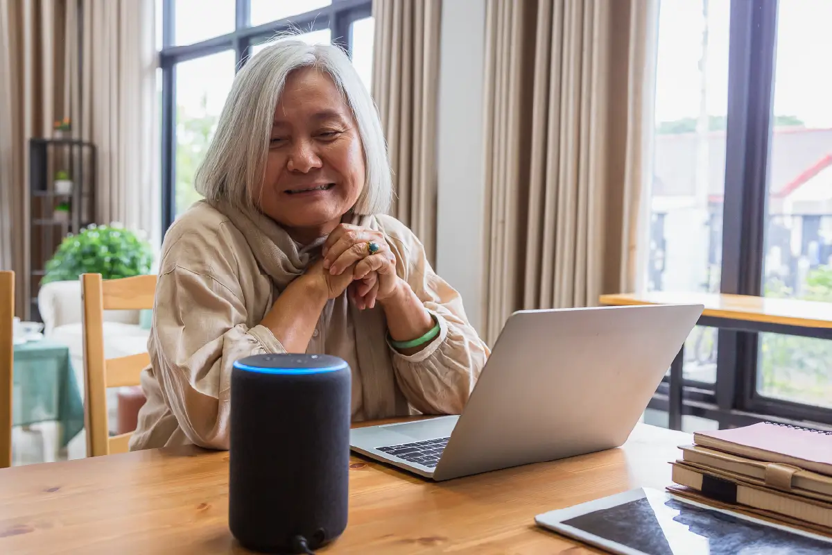 A lady using a voice assistant and a laptop on the table.