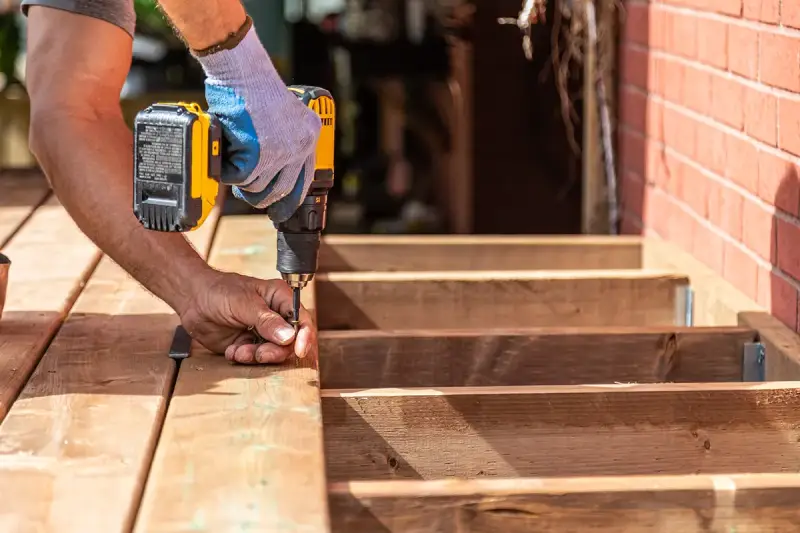 A handyman using a drill to assemble a floating deck.