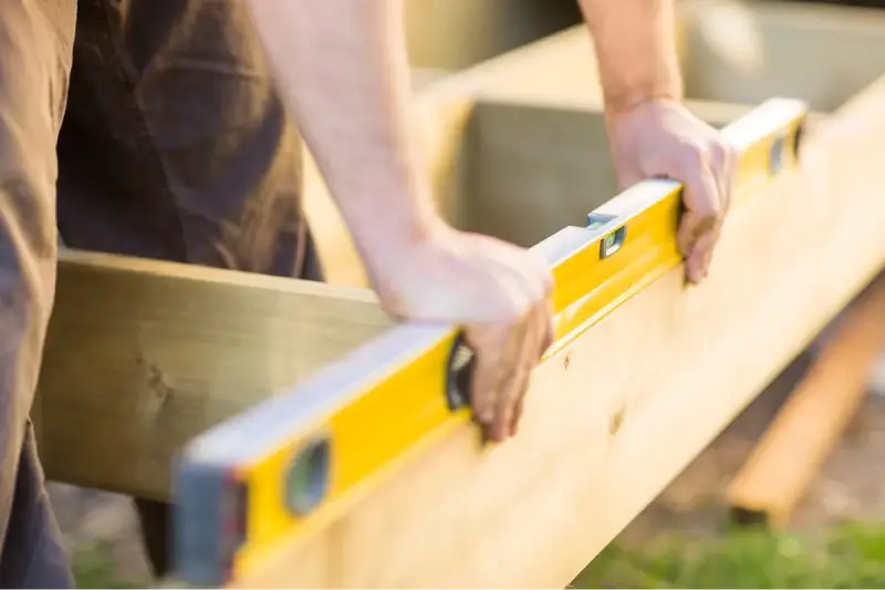 An individual using a level tool to ensure a floating deck is level.