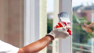 A person painting window trim