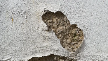 A close-up of damaged stucco on the exterior of a home in need of stucco repair services.