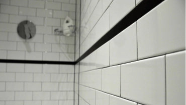 A newly completed residential shower remodel with white tile and black trim.