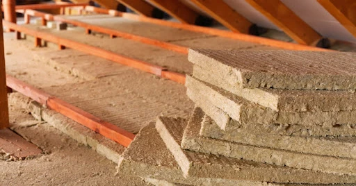 Batts of mineral wool attic insulation stacked together and laid out across the floor of a residential attic.