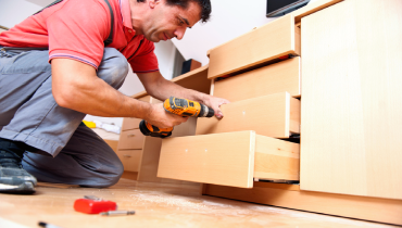 A handyman assembles furniture with power tools.