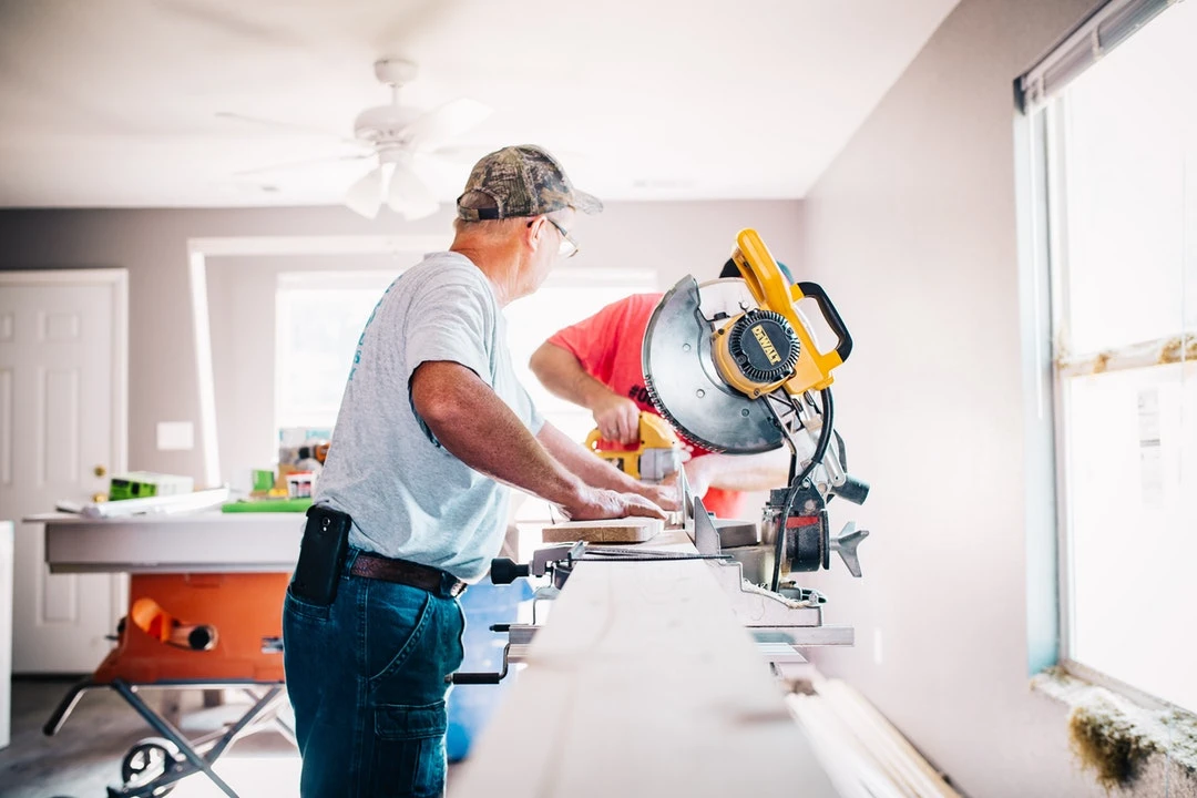 A couple of men working on a table sawing.