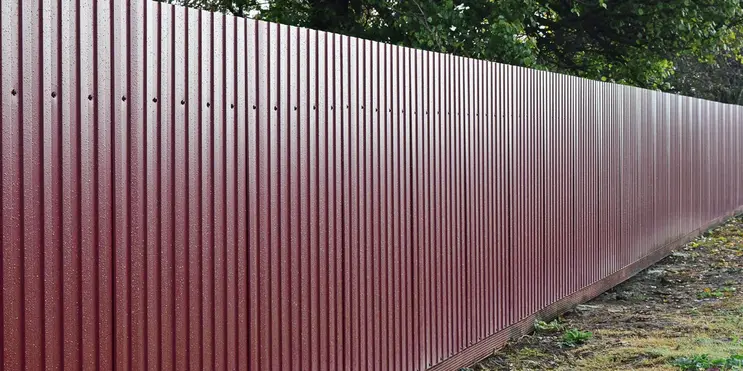 A metal fence running along a property line after fence installation has been completed.