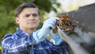 Older man cleaning out gutters