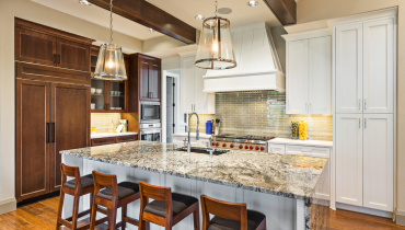 A completed kitchen remodel, with an island bar area, hanging lights, and under-cabinet lighting.