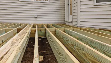 The exposed structure of a front porch before its top boards are replaced during an appointment for porch repair.