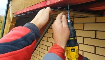 Two handymen providing trim repair services that involve replacing the soffit on a home’s roofline.