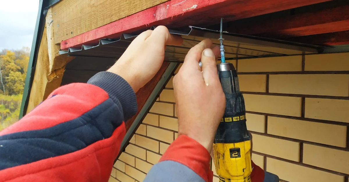 Two handymen providing trim repair services that involve replacing the soffit on a home’s roofline.