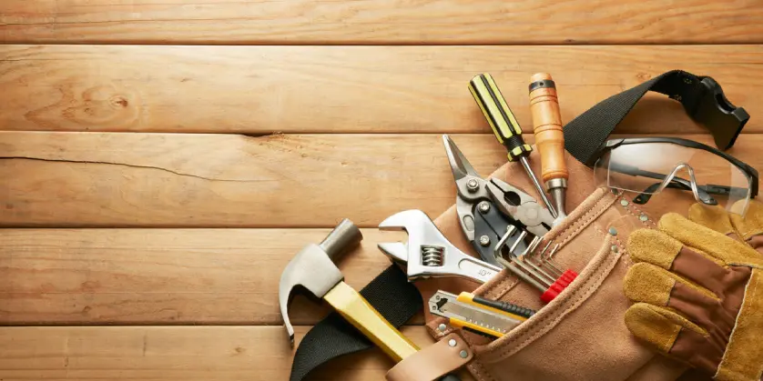 Tools used for carpentry in Naples, FL, and a tool belt lying on top of wooden boards.