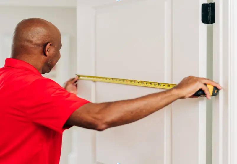 Mr. Handyman service professional measuring an interior door width.