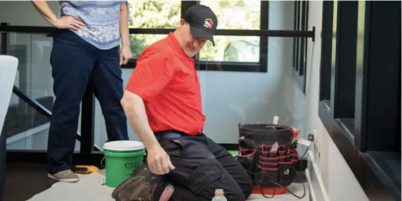 A Mr. Handyman service professional prepares to caulk a window