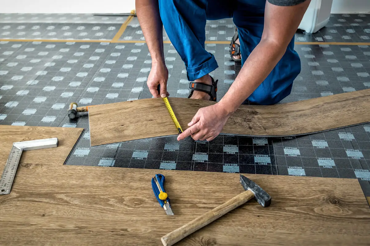 A person installs vinyl flooring planks in a home