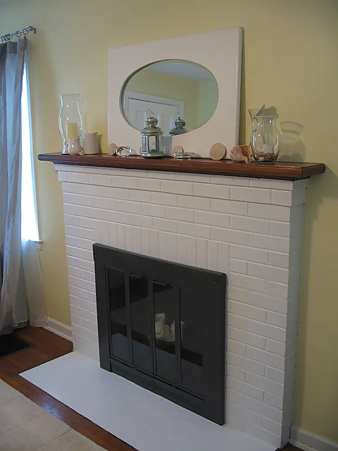 A fireplace with a mirror and candles on top.