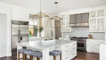 Beautiful white kitchen in luxury home. Features large island, pendant lights, and hardwood floors.