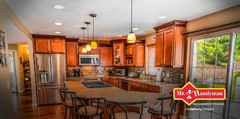 A kitchen with medium-toned wood cabinets, stone backsplash, and tan marble-top island.