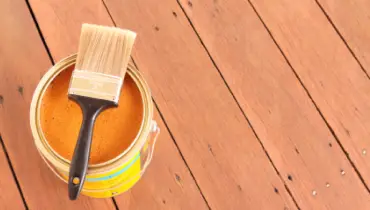 Photo of yellow paint bucket on a wooden deck.