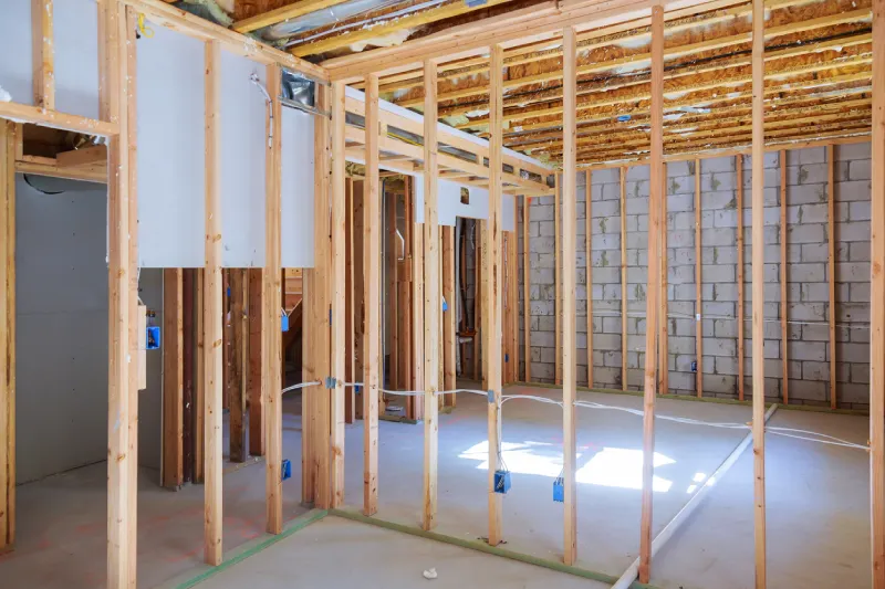 A basement under construction with an unfinished wood frame and a brick wall.