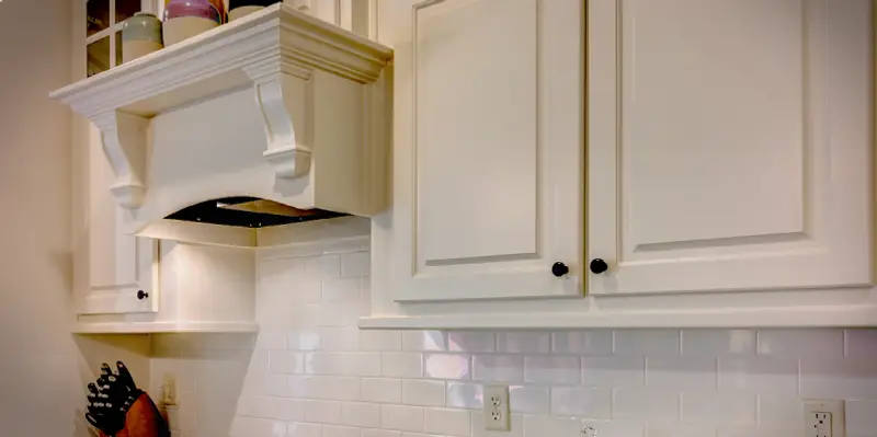 A white kitchen cabinets with black knobs.