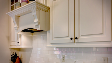 A white kitchen cabinets with black knobs.