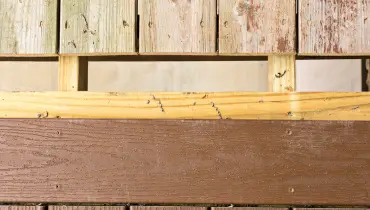 A deck with a gap between its old, weathered boards and the new boards being added during deck repairs.