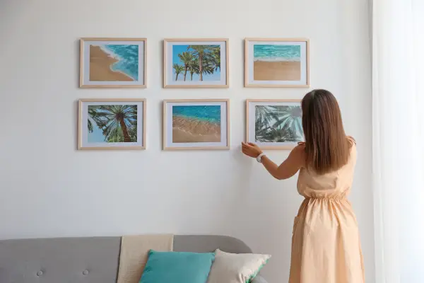 Female interior designer decorating white wall.