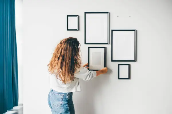 Woman hanging frame on wall .