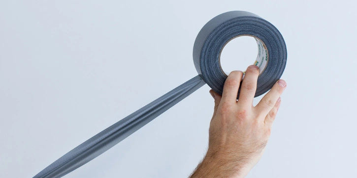 Photo of a hand holding an unrolling duct tape roll.