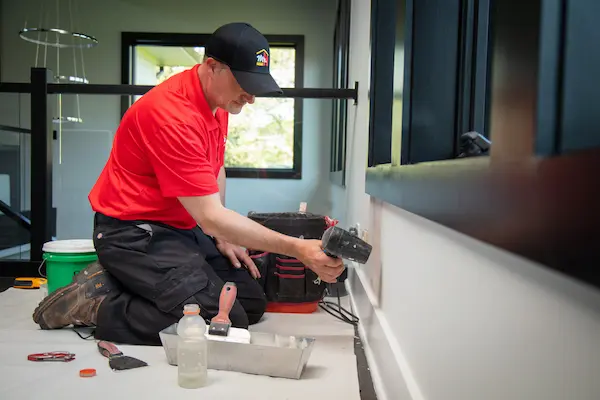 An MRH technician patching drywall in a home.