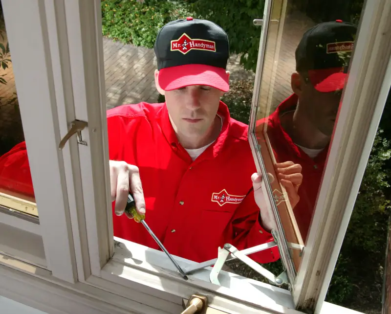 Mr. Handyman employee fixing window.