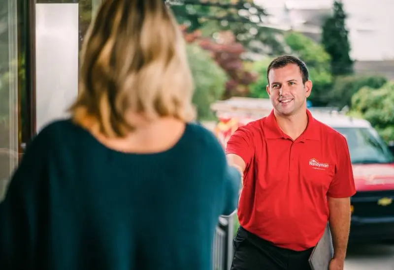 A Mr. Handyman technician being greeted at the door by a customer.