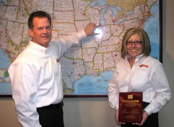 Mr. Handyman of Wheaton-Hinsdale owners in front of map of United States, pointing to Wheaton location and holding plaque.