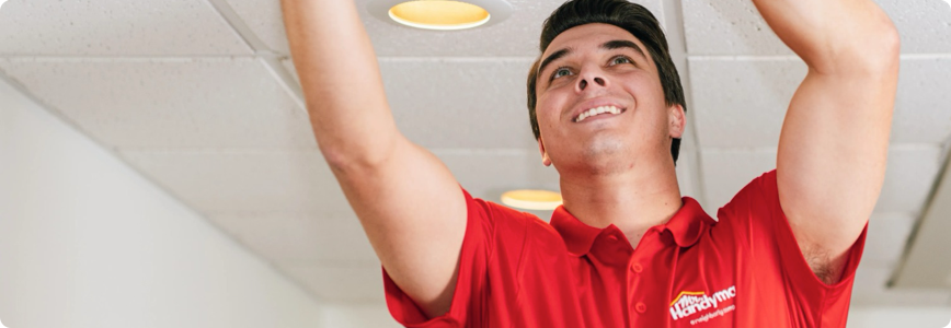 A Mr. Handyman service professional working on a ceiling.