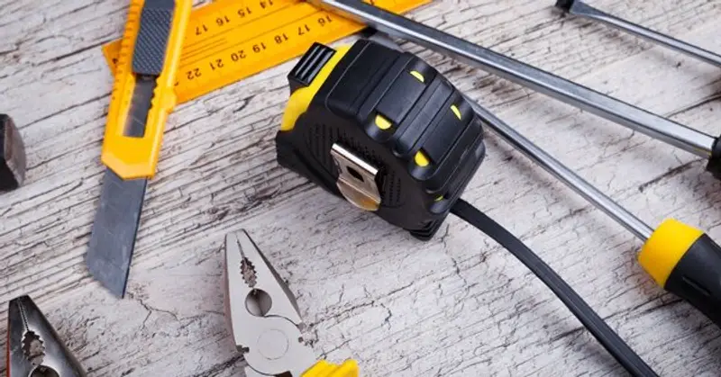 Common hand tools laid out on a wooden surface for use by a handyman in Milton, MA.