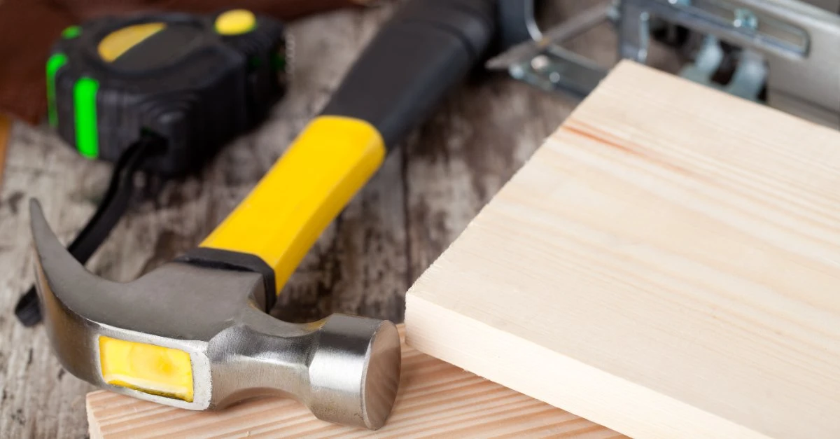 A hammer, two pieces of wood, and a tape measure laid out for use by a professional handyman in Briaroaks, TX.