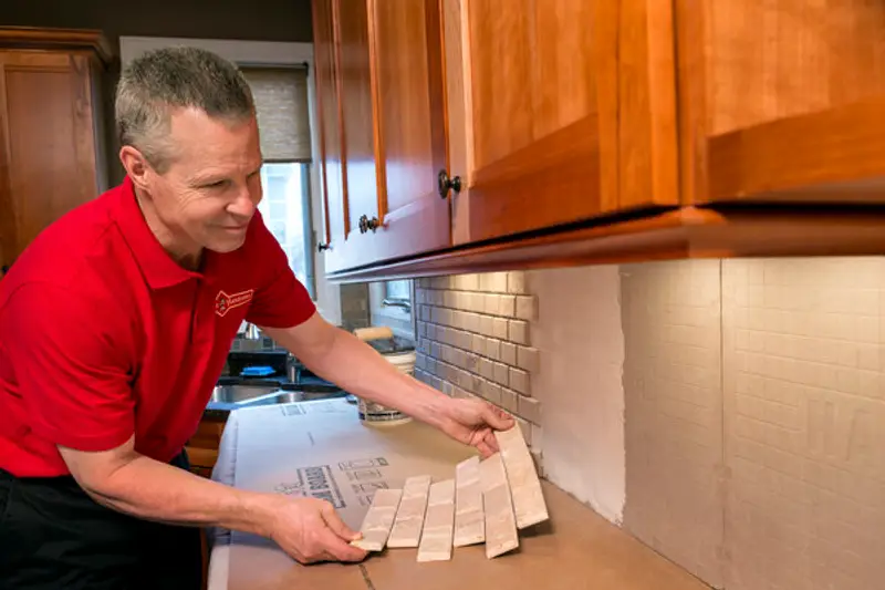 A handyman in Milton, MA laying large sections of tile while installing a new kitchen backsplash. 