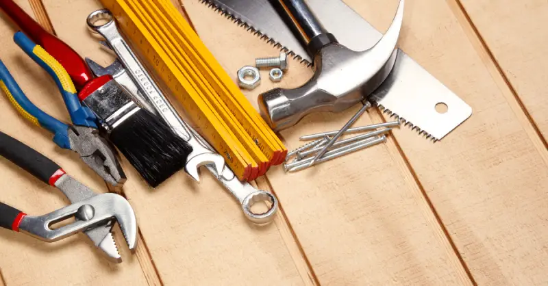 A collection of tools that are commonly used by a handyman in Quincy, MA, including a hammer, hand saw, nails, screws, a brush, and a ruler set.