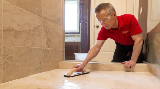 Mr. Handyman technician repairing grout in Norfolk shower.