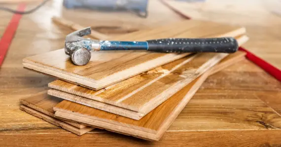 A hammer placed on several replacement floor boards before being used for flooring repair in Keller, TX.