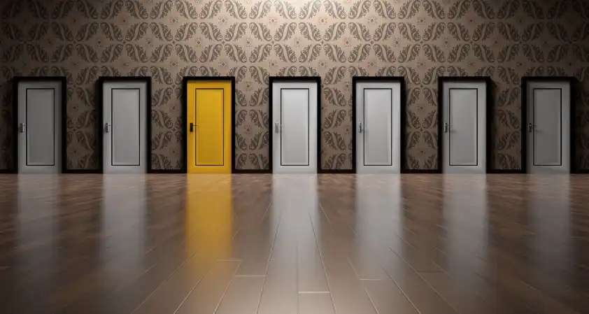 A row of white doors and a single yellow door inside of a building where interior door installation has been completed.