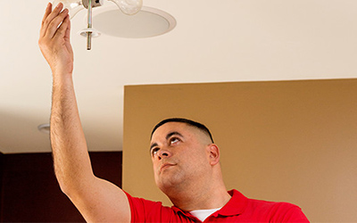 Handyman installing light fixture.