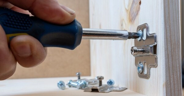 A handyman using a screwdriver to install new cabinet door hinges during an appointment for cabinet repair in frisco, TX.