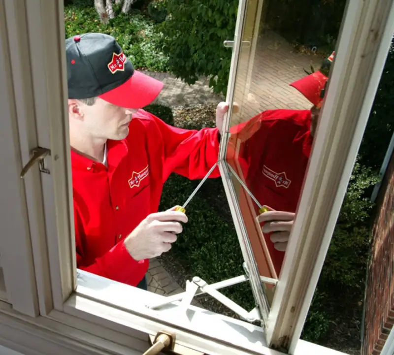 A handyman from Mr. Handyman replacing the mesh screen of a window during an appointment for window repairs.